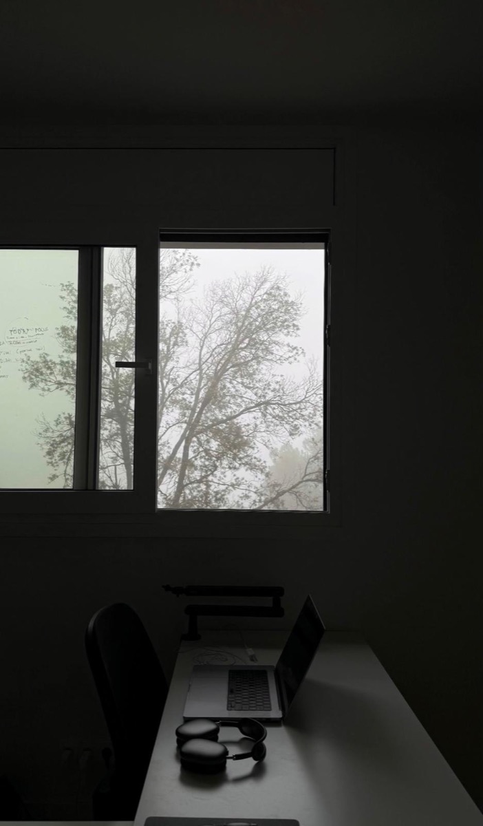 Schreibtisch mit Laptop und Kopfh&ouml;rern, Nebel vor dem Fenster